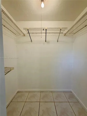 a view of an empty room with window and chandelier fan
