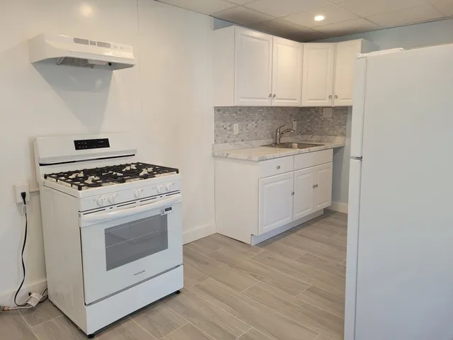 a kitchen with granite countertop white cabinets and white appliances