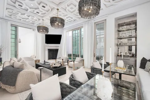 a living room with furniture a fireplace and a chandelier