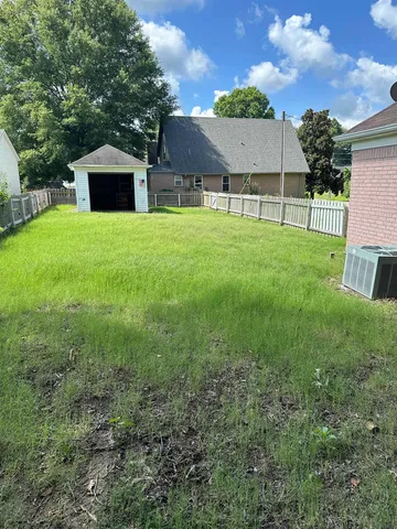 a view of a house with backyard and a tree
