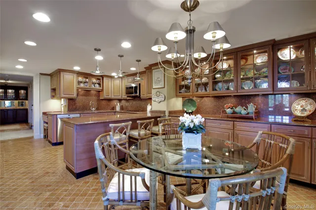 a kitchen with stainless steel appliances granite countertop a sink a refrigerator and chairs