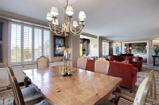 a view of a dining room with furniture a chandelier and large windows