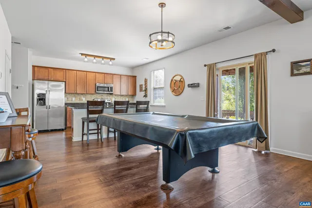 a kitchen with stainless steel appliances granite countertop a stove top oven a refrigerator a sink and a table