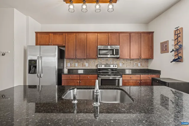 a kitchen with stainless steel appliances granite countertop a refrigerator a sink a stove and island