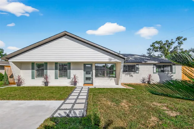 a front view of a house with a yard and potted plants