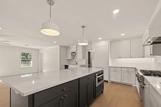 a kitchen with kitchen island granite countertop a sink a stove a oven a counter space and cabinets