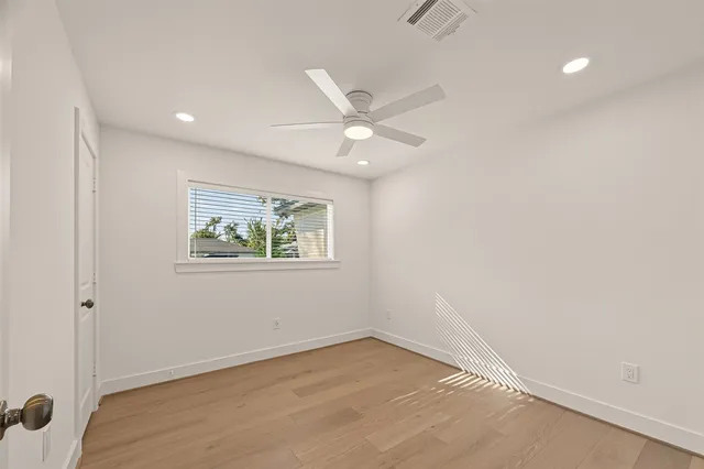 an empty room with wooden floor and ceiling fan