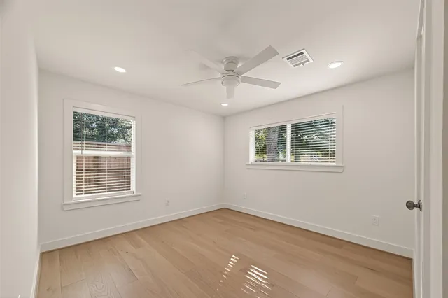 an empty room with wooden floor and fan