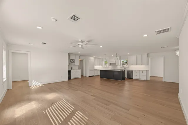 a view of a kitchen with kitchen island a sink stainless steel appliances and white cabinets
