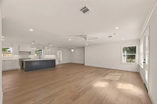 a large white kitchen with kitchen island a sink dishwasher a stove and a refrigerator with wooden floor