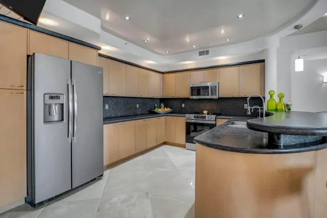 a kitchen with stainless steel appliances granite countertop a sink a refrigerator and a stove