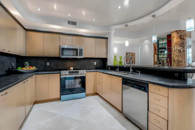 a kitchen with stainless steel appliances granite countertop a refrigerator a stove and a sink with wooden floor