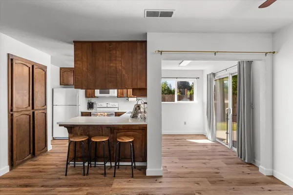 a kitchen with stainless steel appliances a dining table chairs refrigerator and sink