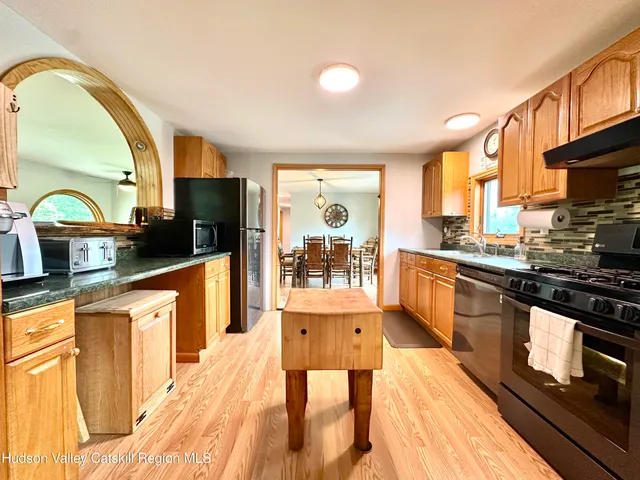 a large kitchen with stainless steel appliances granite countertop a stove a sink dishwasher and cabinets with wooden floor