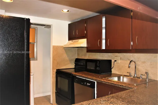 a kitchen with stainless steel appliances granite countertop a sink and a refrigerator