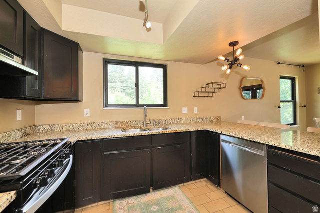 3104 East High Danish Road Sandy, UT 84093 - Photo 7 of 36 Kitchen featuring dark wood cabinetry, light speckled countertops, stainless steel appliances, and a gas range