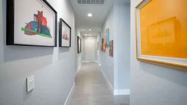 a view of a hallway with paintings on the wall and a large window