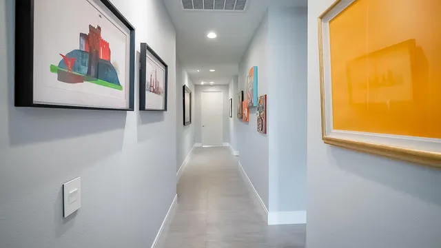 a view of a hallway with paintings on the wall and a large window