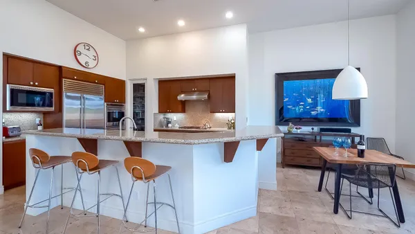 a kitchen with stainless steel appliances kitchen island granite countertop a table chairs sink and cabinets