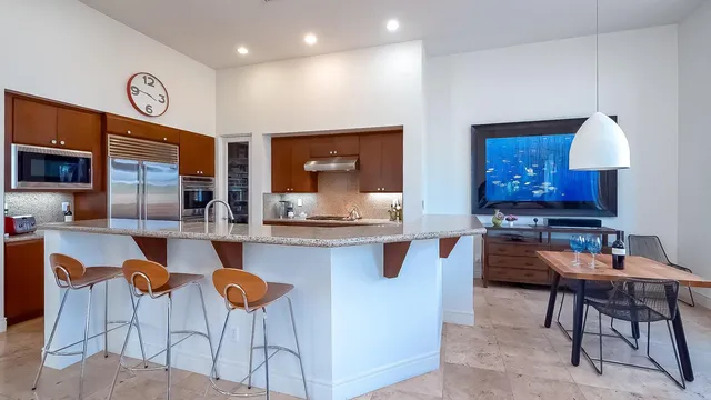 a kitchen with stainless steel appliances kitchen island granite countertop a table chairs sink and cabinets
