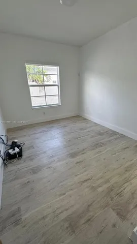 an empty room with wooden floor and a window