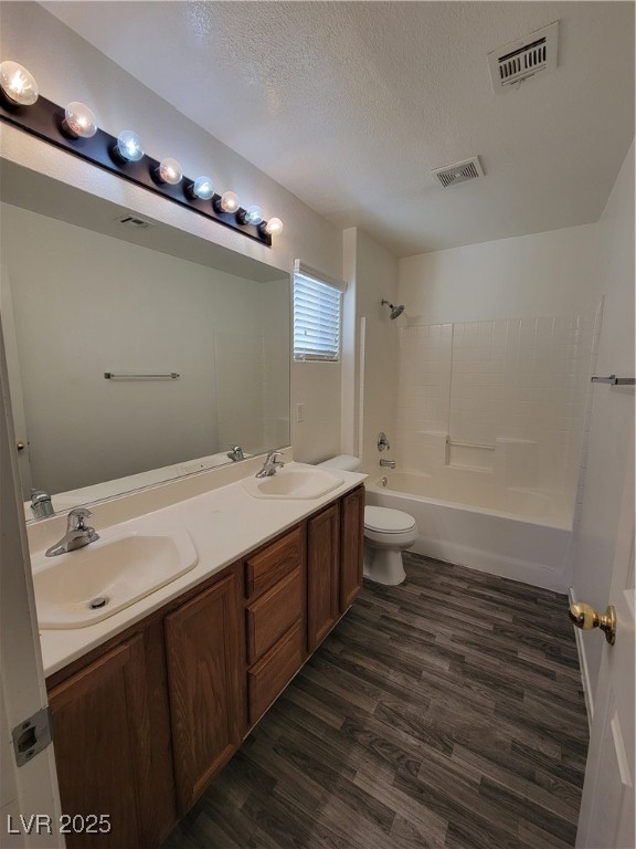 1112 Nevada Blaze Avenue North Las Vegas, NV 89081 - Photo 15 of 22 Bathroom featuring bathing tub / shower combination, double vanity, dark wood-style floors, and a textured ceiling