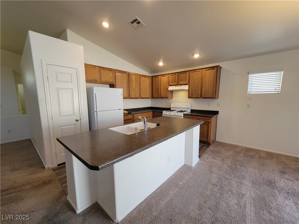 1112 Nevada Blaze Avenue North Las Vegas, NV 89081 - Photo 2 of 22 Kitchen featuring dark countertops, dark carpet, white appliances, an island with sink, and recessed lighting