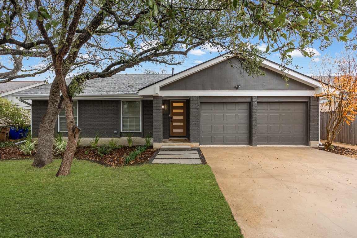 View of front of home featuring concrete driveway, brick siding, a front yard, and an attached garage