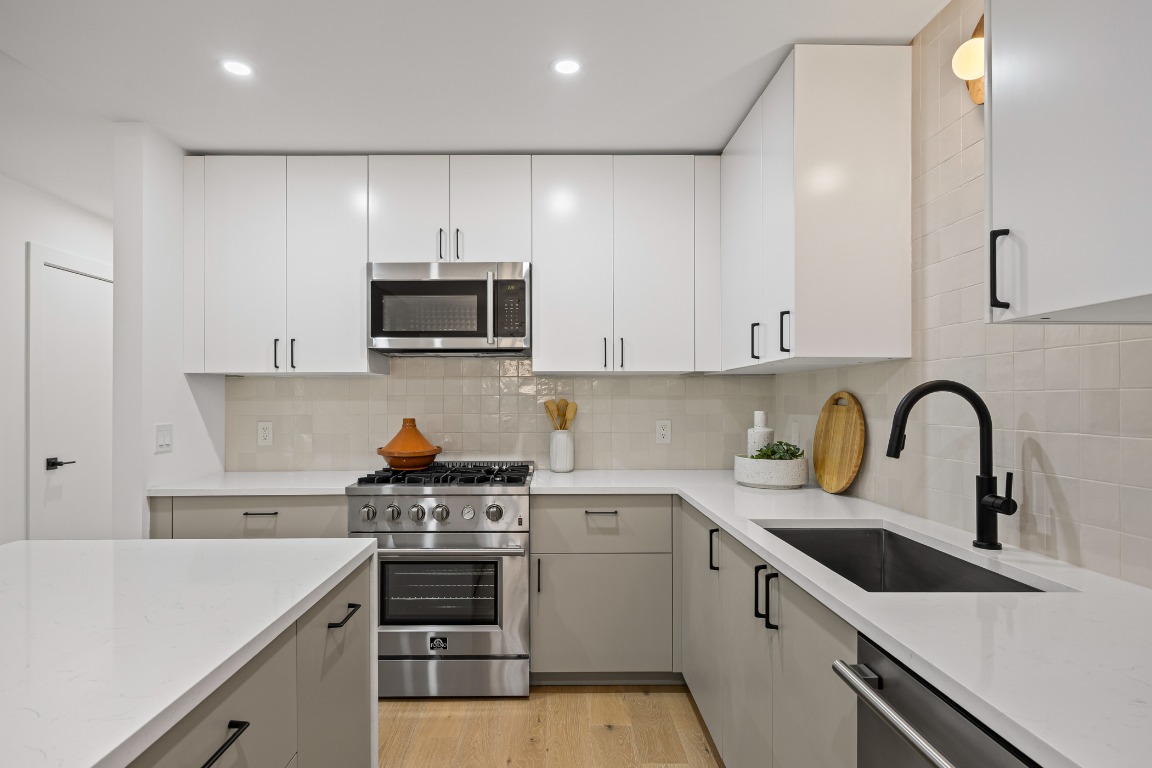 4609 Cliffstone Cove Austin, TX 78735 - Photo 11 of 33 Kitchen with stainless steel appliances, light wood-style flooring, tasteful backsplash, light stone countertops, and gray cabinetry