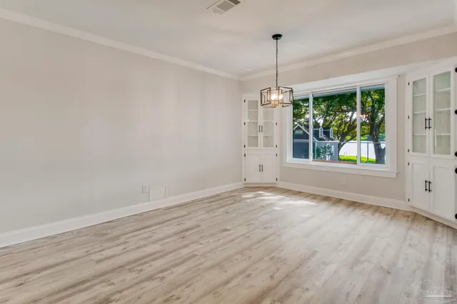 a view of an empty room with window and wooden floor