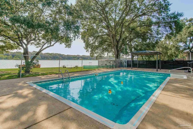 a view of a swimming pool with a patio and a yard