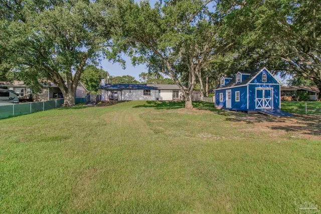 a view of a house with a big yard and large trees