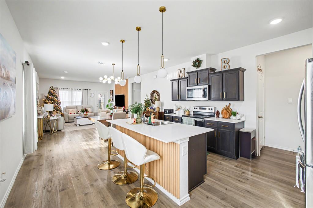 1301 Draper Lane Forney, TX 75126 - Photo 13 of 33 a kitchen with stainless steel appliances kitchen island granite countertop a sink a stove and a wooden floors