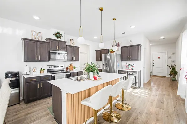 a kitchen with stainless steel appliances kitchen island granite countertop a sink a stove a dining table and chairs
