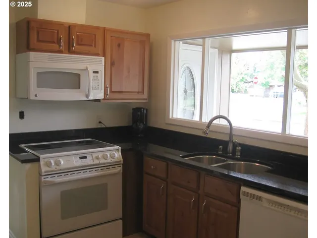 a kitchen with granite countertop a sink stove and cabinets