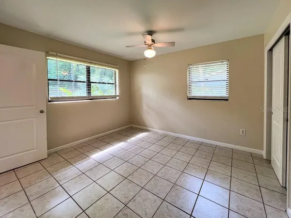 a view of an empty room window and chandelier fan