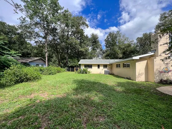 a view of a house with a yard and a large tree