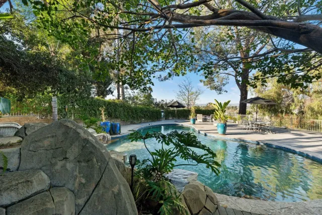 a aerial view of a house with yard lake and trees all around