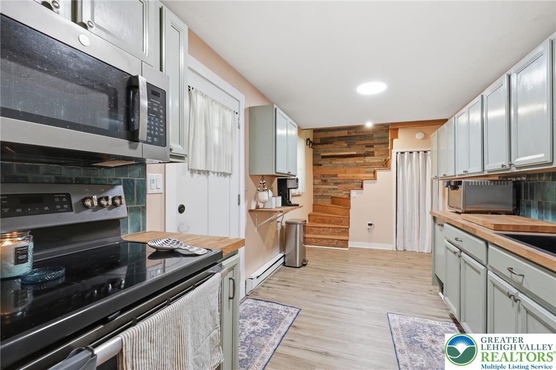9033 Loop Road Slatington, PA 18080 - Photo 25 of 53 A well-equipped culinary space featuring an electric range and microwave, complemented by light gray cabinetry and wood-look flooring.