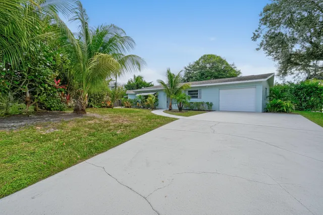 a view of a house with a yard and palm trees