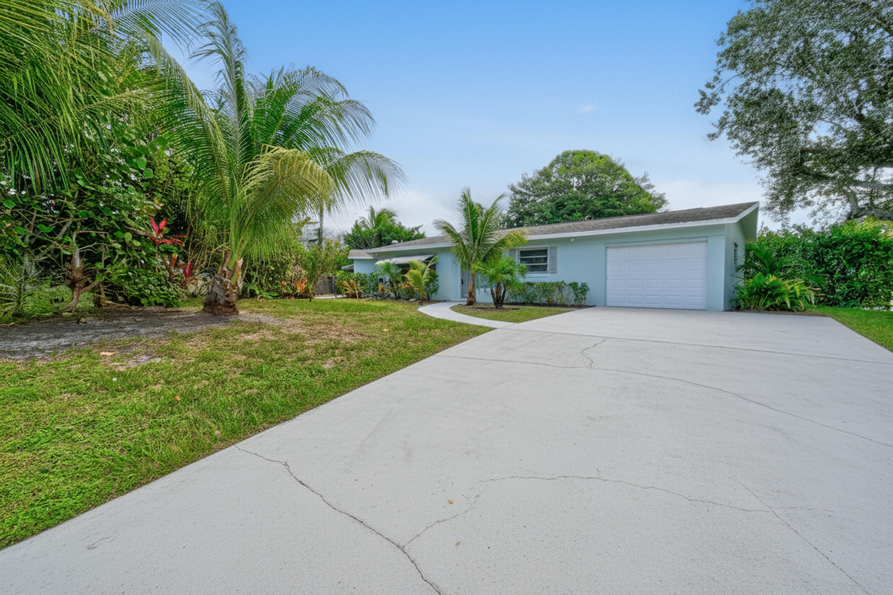 a view of a house with a yard and palm trees