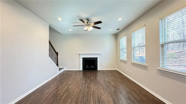 an empty room with windows fireplace and wooden floor