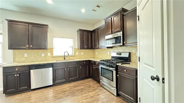 a kitchen with stainless steel appliances granite countertop wooden cabinets granite counter tops and a window