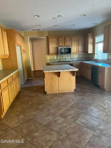 a large kitchen with stainless steel appliances a stove a sink a microwave a counter top and cabinets