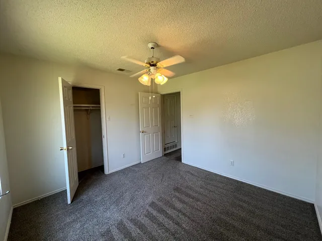 an empty room with a chandelier fan and wooden floor