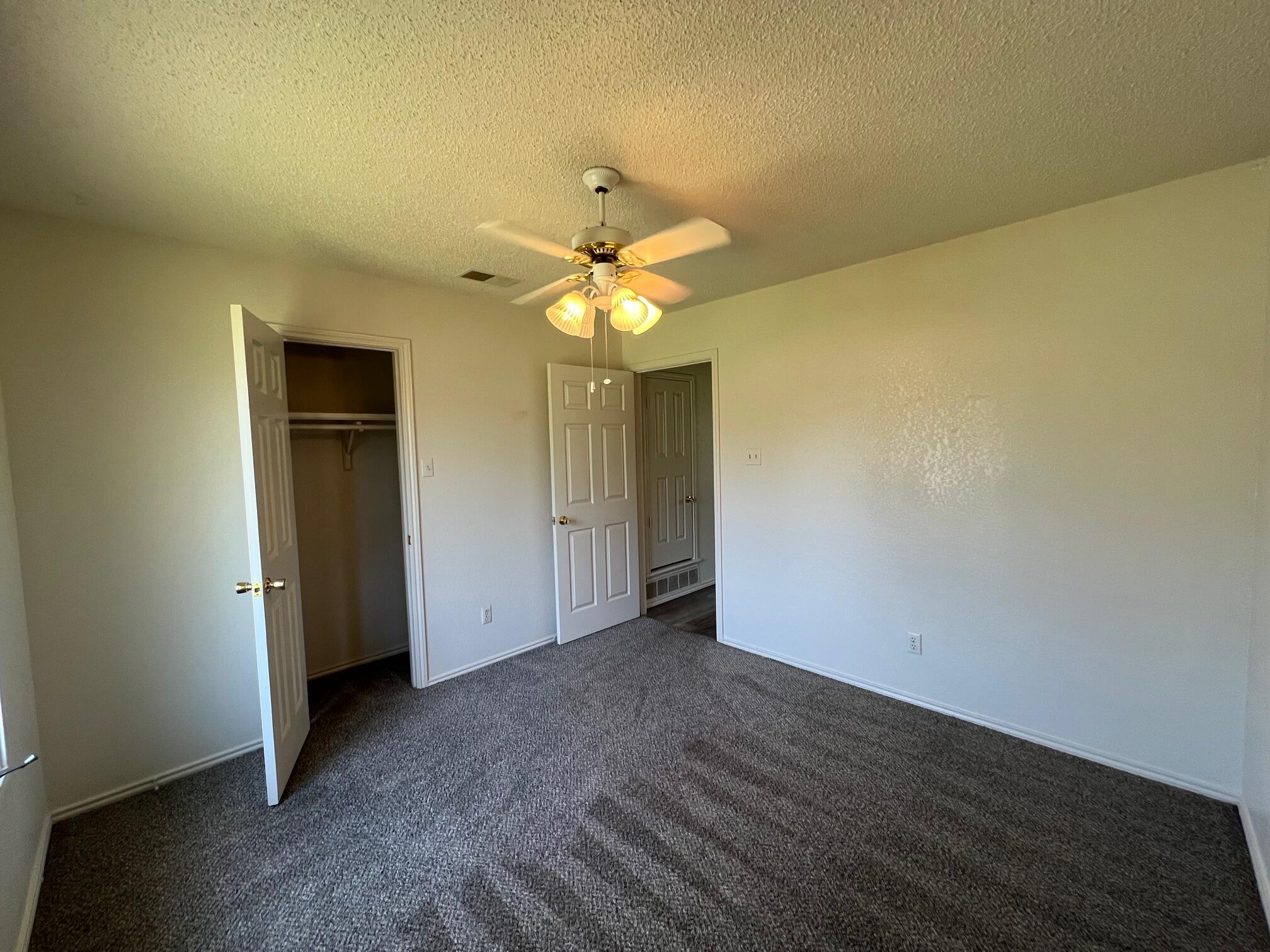 5522 95th Street Lubbock, TX 79424 - Photo 18 of 26 an empty room with a chandelier fan and wooden floor