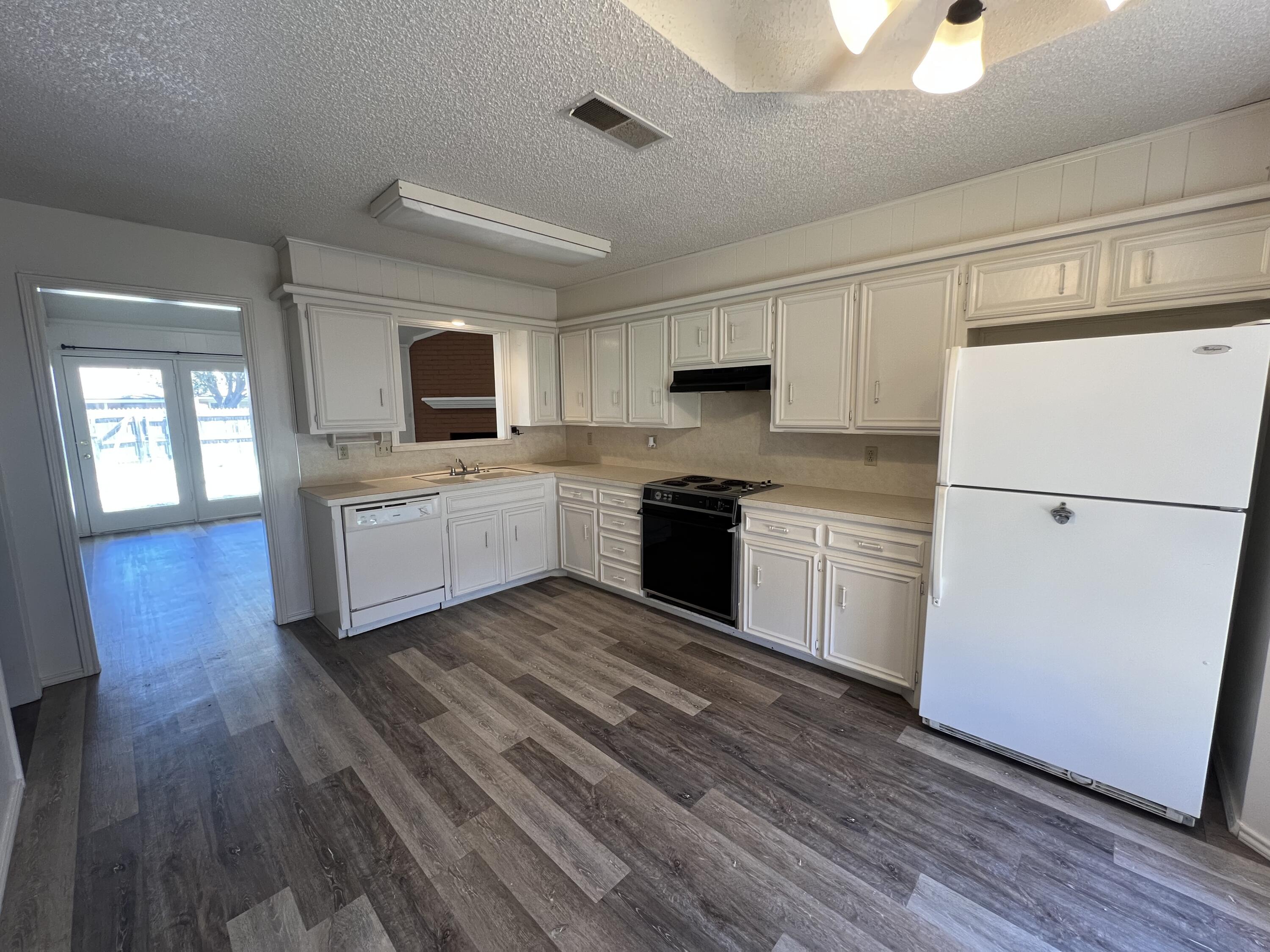 5522 95th Street Lubbock, TX 79424 - Photo 9 of 26 a kitchen with a refrigerator a stove top oven a sink dishwasher and wooden floor