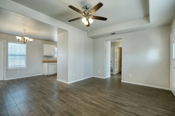a view of an empty room with window and wooden floor