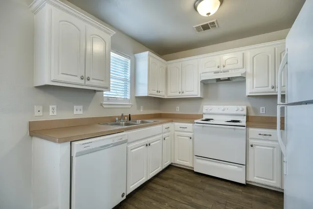 a kitchen with stainless steel appliances granite countertop a sink and cabinets with wooden floors