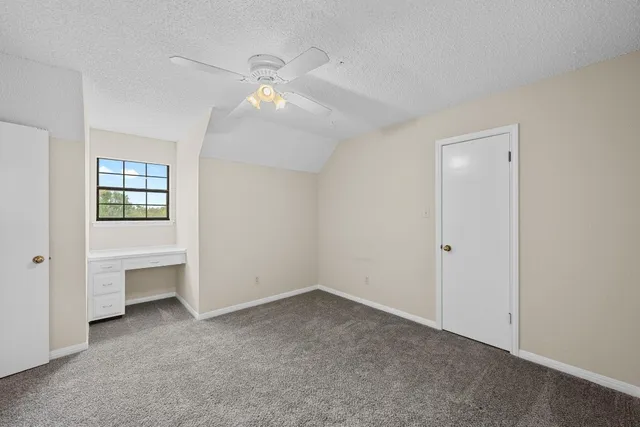 an empty room with chandelier fan and windows